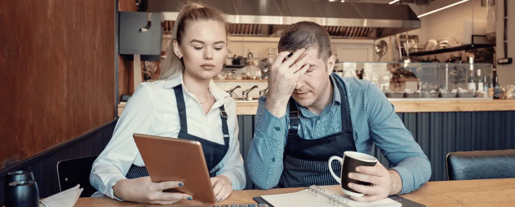 two restaurant business owners looking at tablet upset