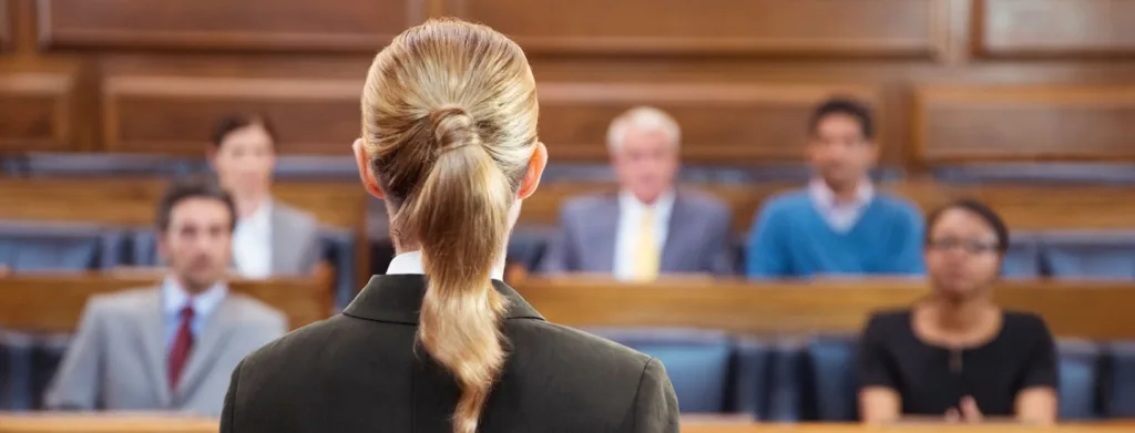 back of white female attorney who is facing courtroom audience